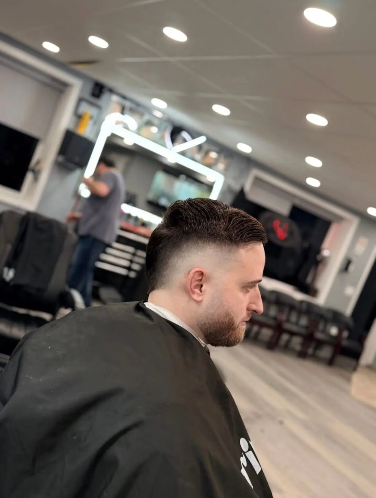 Slicked-back cut with a high skin fade and a trimmed beard
